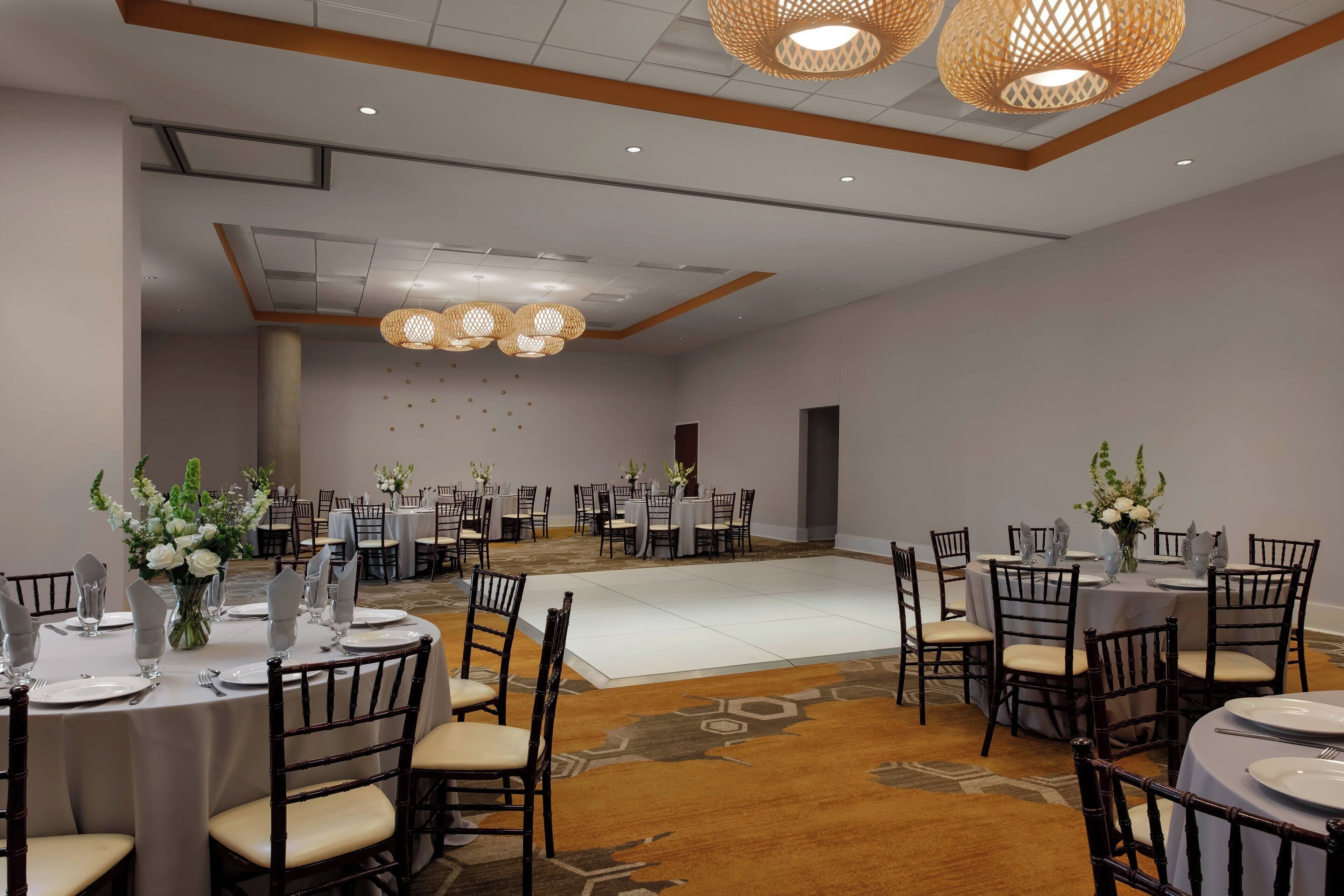 Un salón de banquetes con mesas redondas, sillas y candelabros.