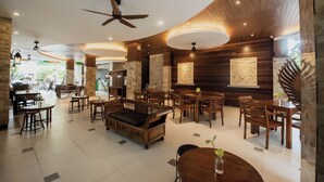 A spacious lobby with wooden furniture, a ceiling fan, and artwork on the walls. - Sandat Hotel Legian (Kuta)