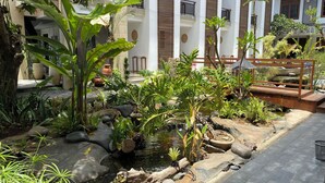 A serene garden with a small pond, surrounded by various plants and rocks. - Sandat Hotel Legian (Kuta)