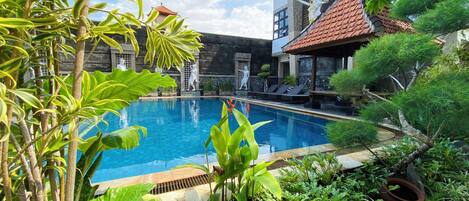 Una piscina al aire libre, sillones reclinables de piscina