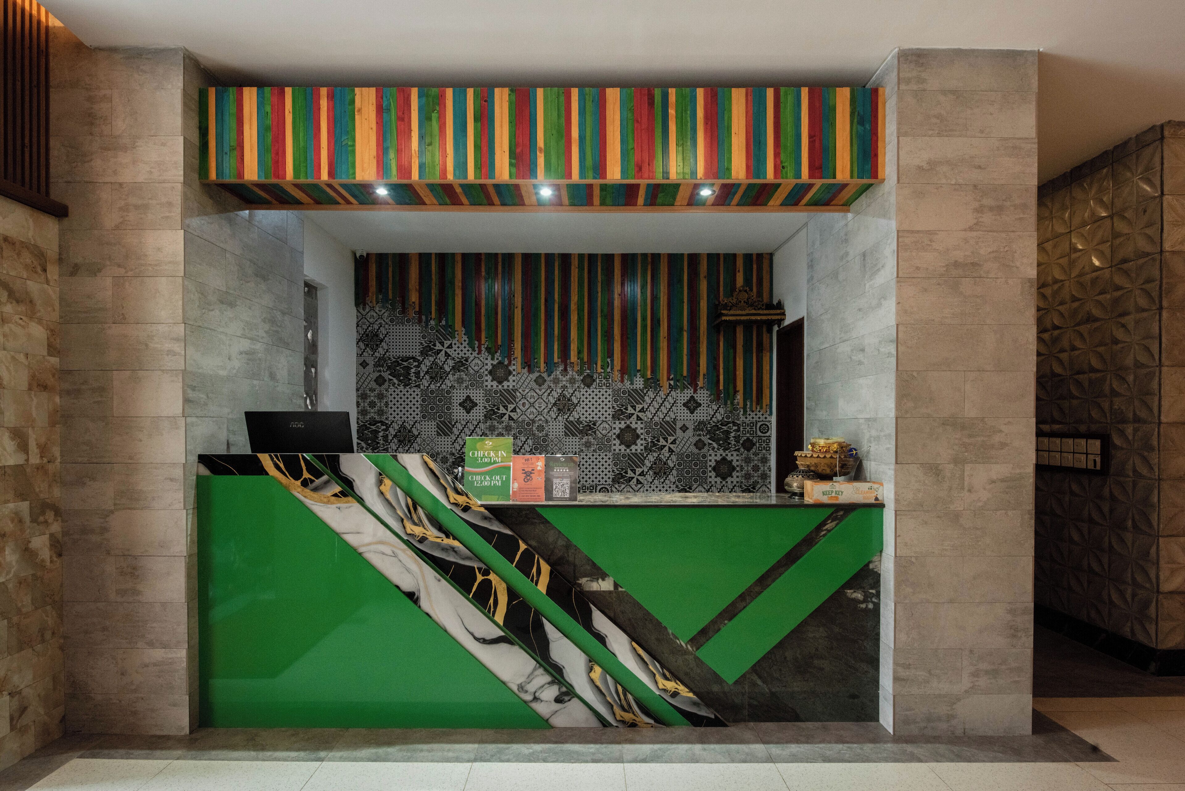 A reception desk with a green and white color scheme, a patterned wall behind it, and a wooden slat ceiling.