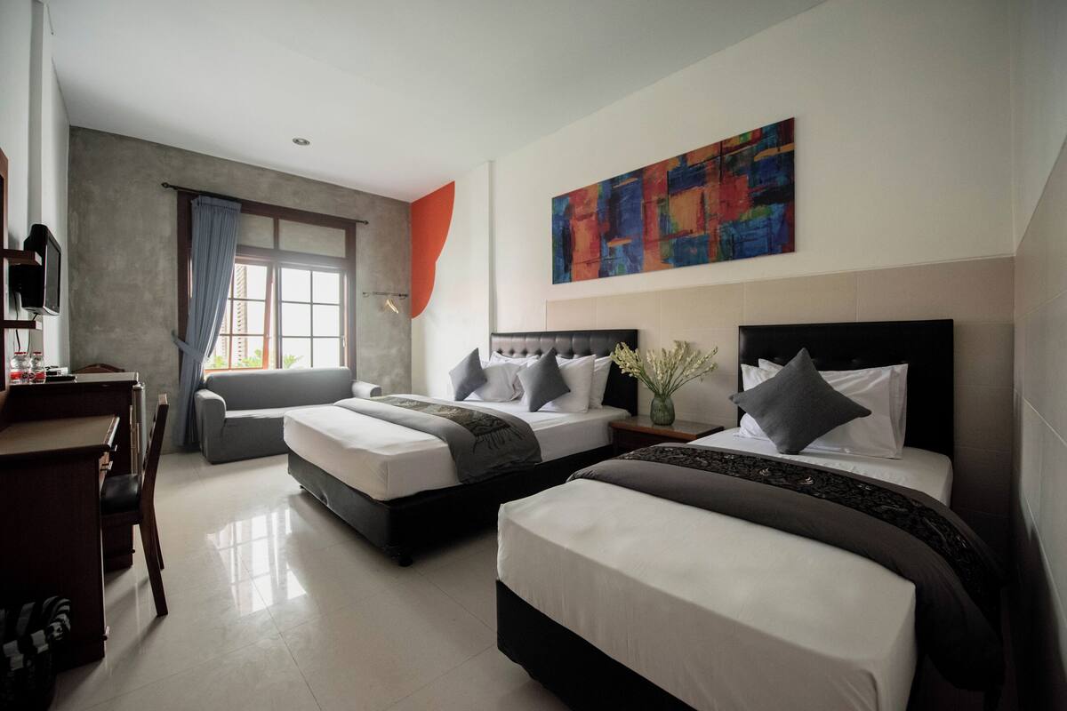A modern hotel room with two beds, a desk, and a large window with curtains.