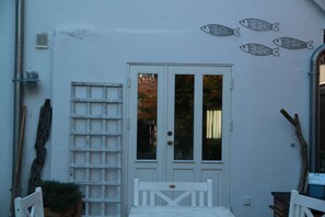 A white door with a grid pattern, a white bench, and a wall with fish decorations.