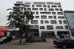Ein mehrstöckiges Hotel mit modernem architektonischen Design, ein zentraler Eingang mit einem Schild und mehrere Autos vor der Fassade.