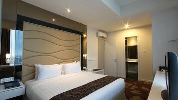 Une chambre d’hôtel avec un grand lit, un bureau avec un ordinateur, une télévision et une salle de bain équipée d’un miroir et d’un lavabo.