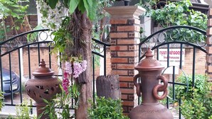 Un área ajardinada con plantas en macetas, un árbol grande y una estructura de ladrillo.