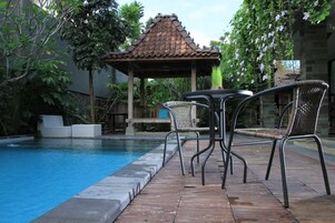 Un área de piscina con solárium empinado, un pabellón y sillas de mimbre.