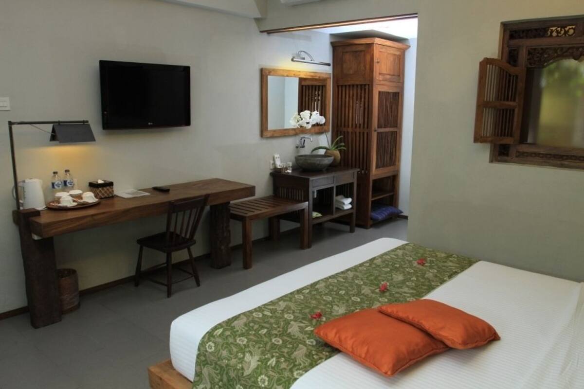 Een slaapkamer met een bed, een bureau, een stoel, een televisie en een kledingkast.