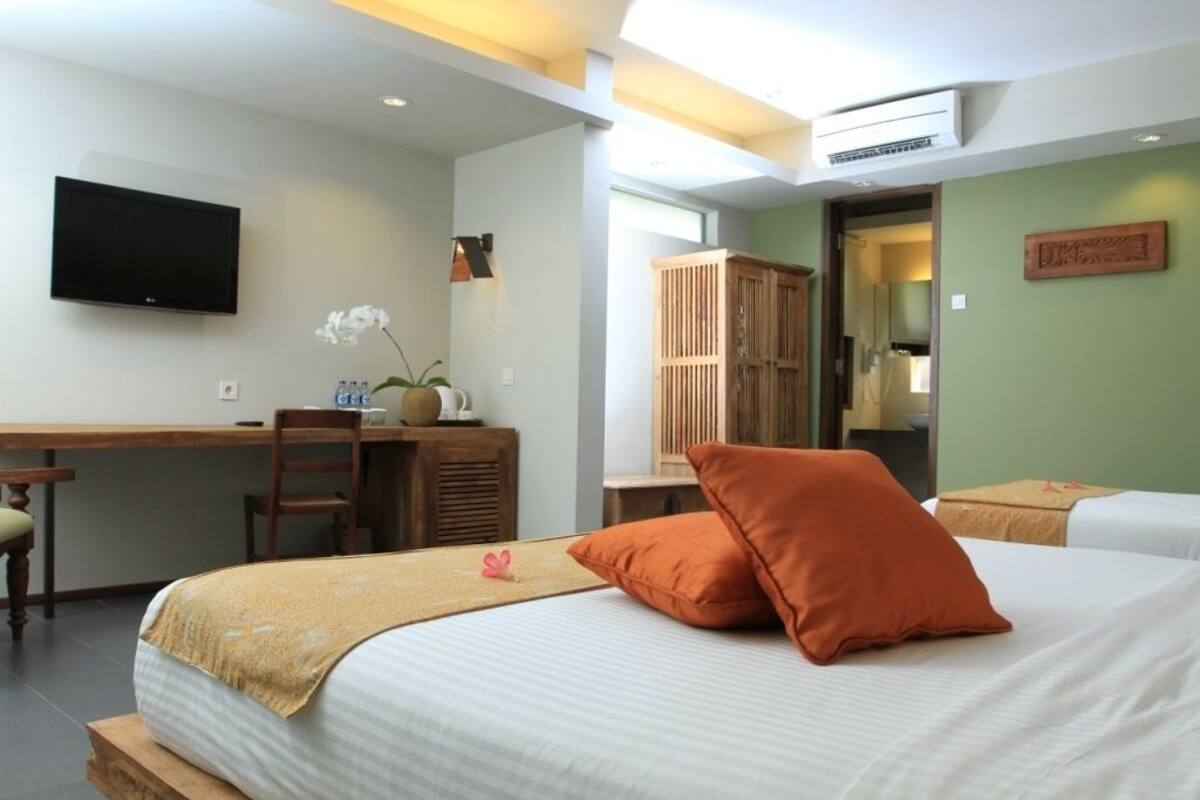Een hotelkamer met een bed, een bureau met stoel, een televisie en een kledingkast.