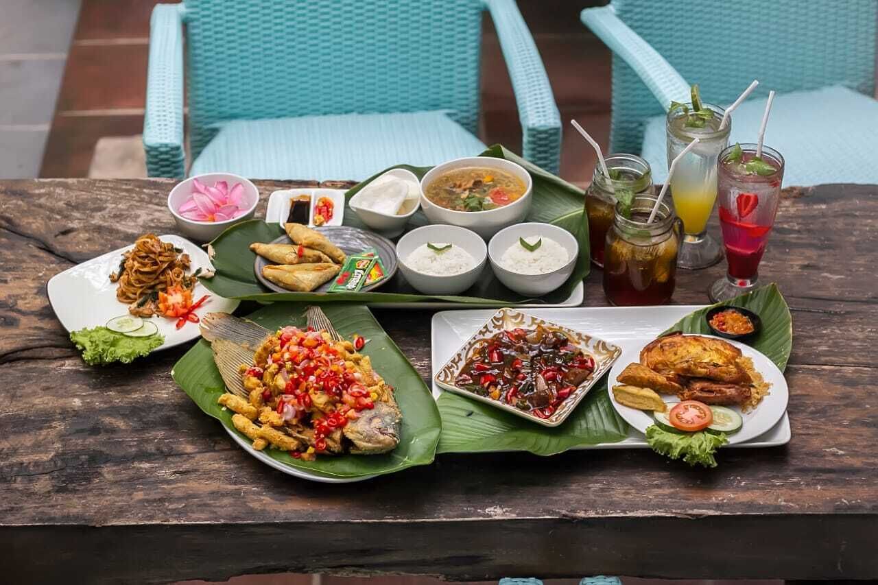A table set with various dishes, drinks, and condiments, likely in an outdoor dining area.