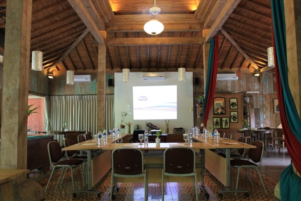 A conference room with a long table, chairs, and a projector screen.