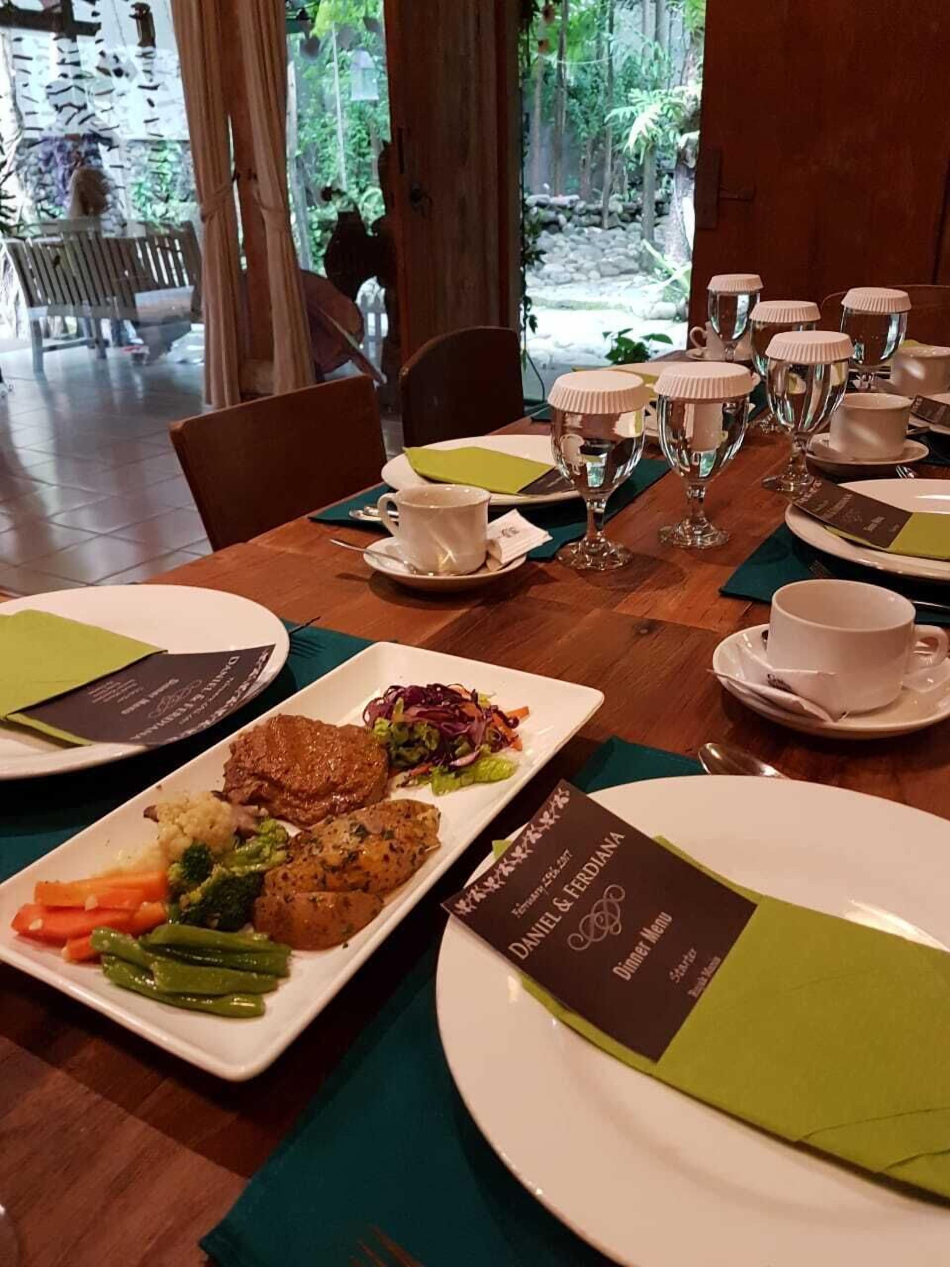 A dining table set with plates of food, glasses, and a menu.
