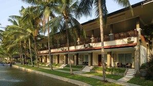 A hotel with a pool, palm trees, and a two-story structure with balconies. - Hotel Puri Asri (Magelang)