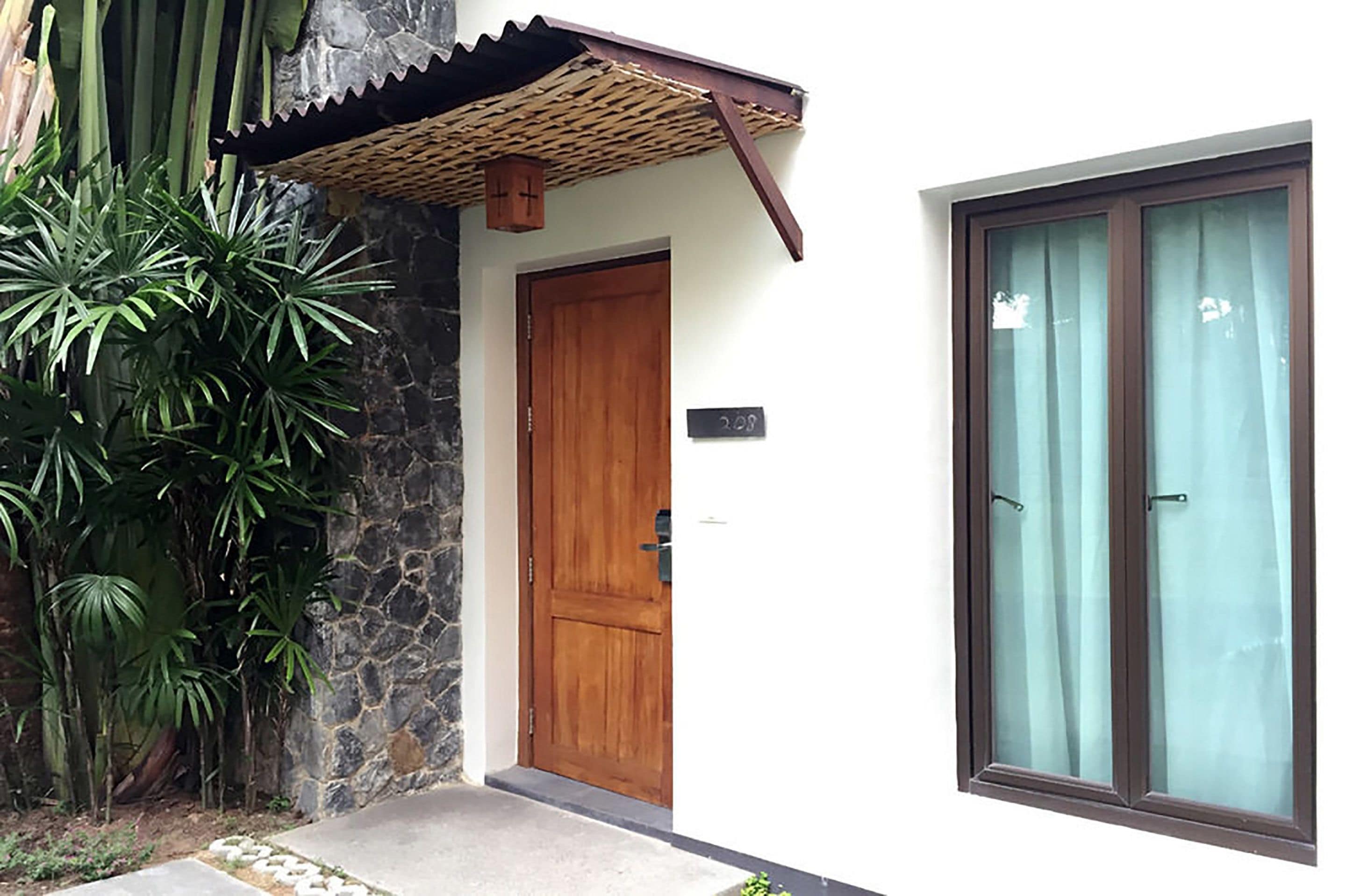 A wooden door, a stone wall, and a window with curtains.