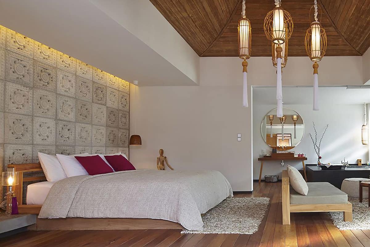 Ein Schlafzimmer mit einem großen Bett, einer Holzbalkendecke und einer dekorativen Wandverkleidung.