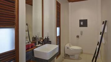 A modern bathroom with a large mirror, a white sink, a toilet, and a towel rack.