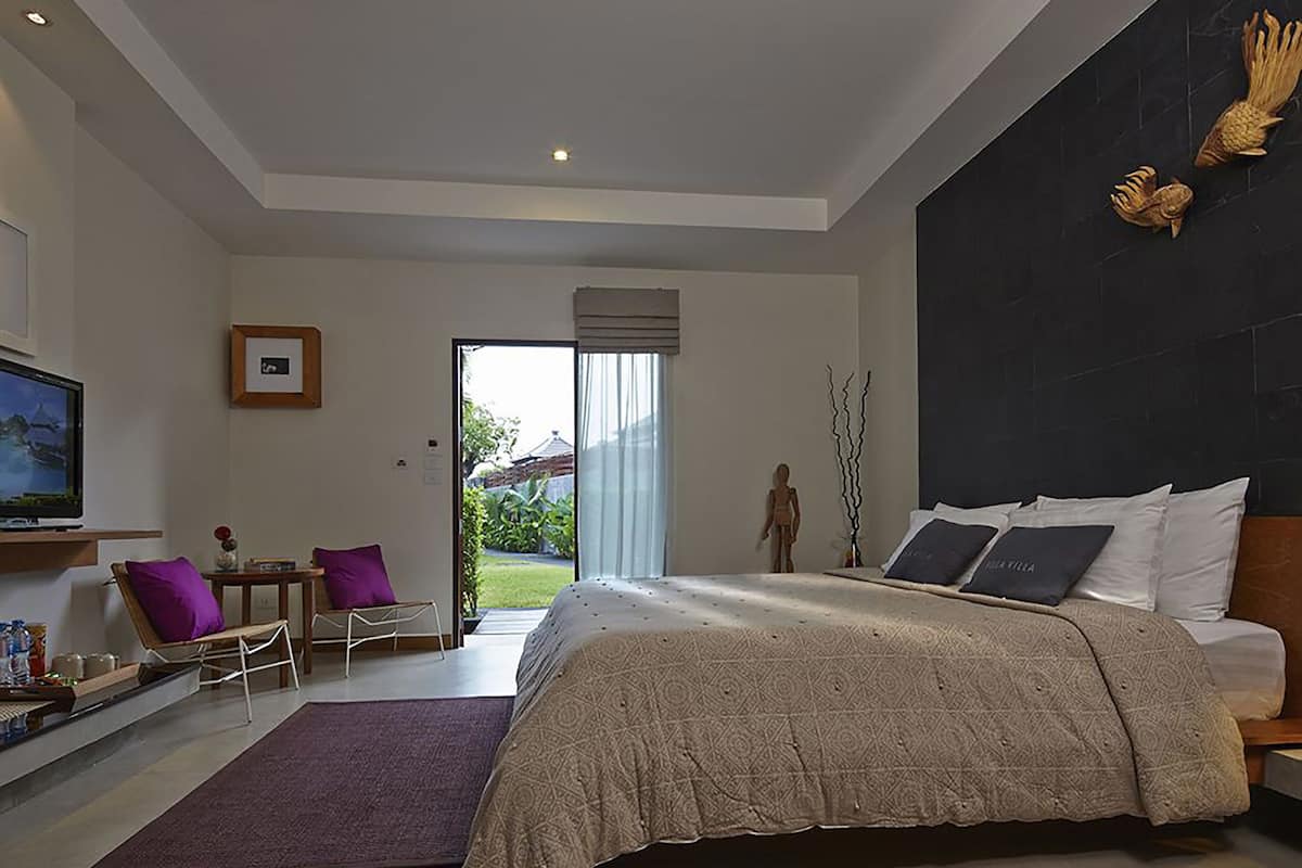Ein modernes Schlafzimmer mit einem großen Bett, einem Fernseher, einem Schreibtisch und Blick ins Freie.