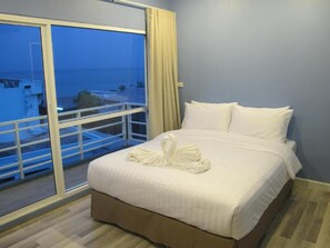Habitación de hotel con cama, balcón con barandilla y vista al mar.