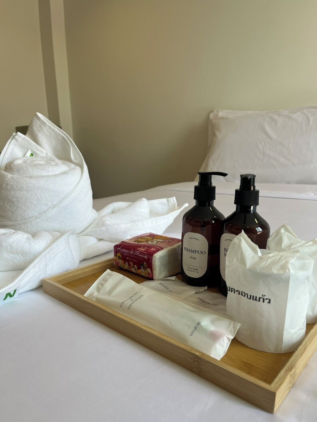 Habitación de hotel con una cama bien hecha, un atril con artículos de aseo como champú, una pastilla de jabón y una caja de pañuelos.
