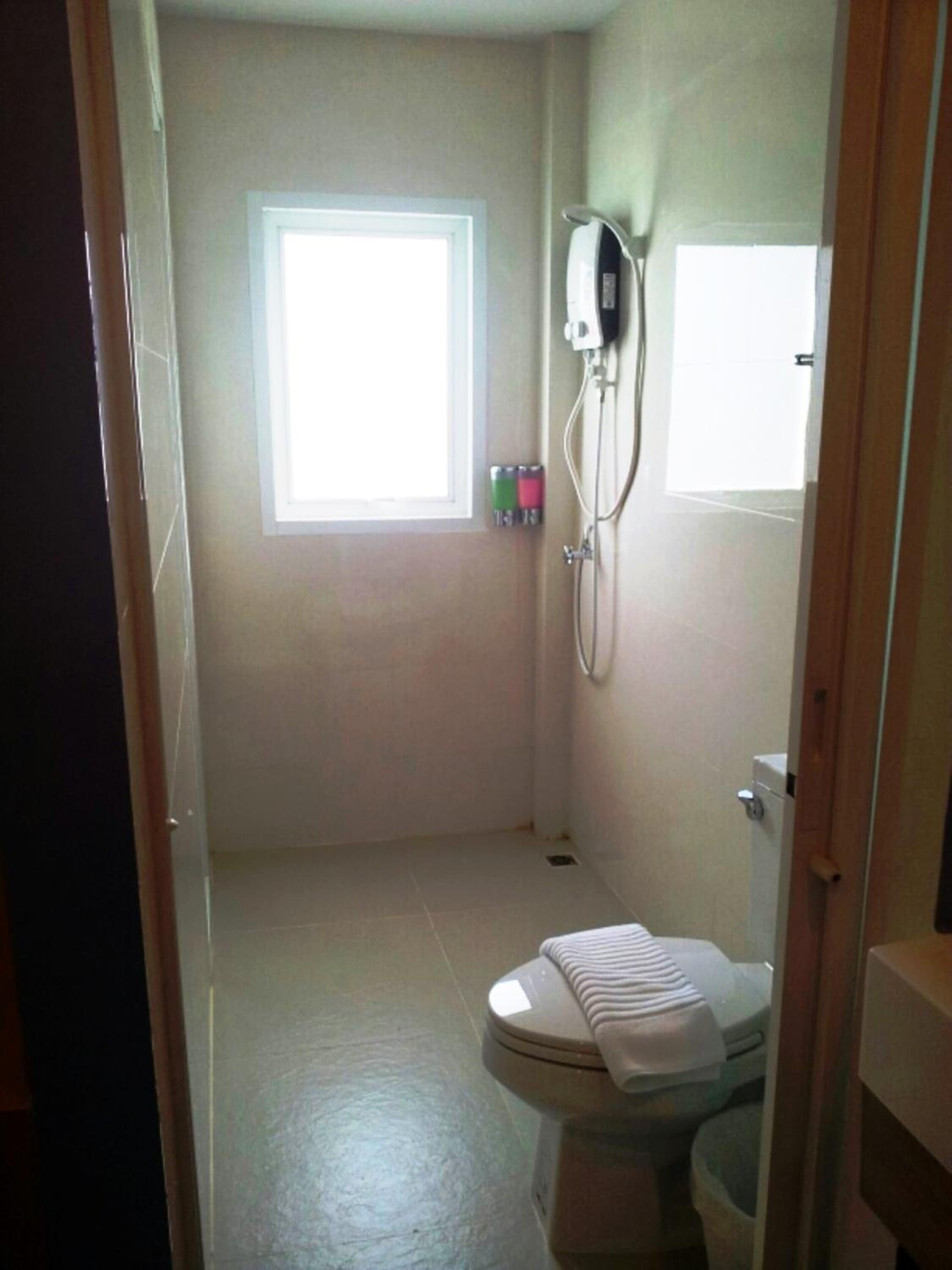 Une petite salle de bain avec des toilettes, une fenêtre et une douche.