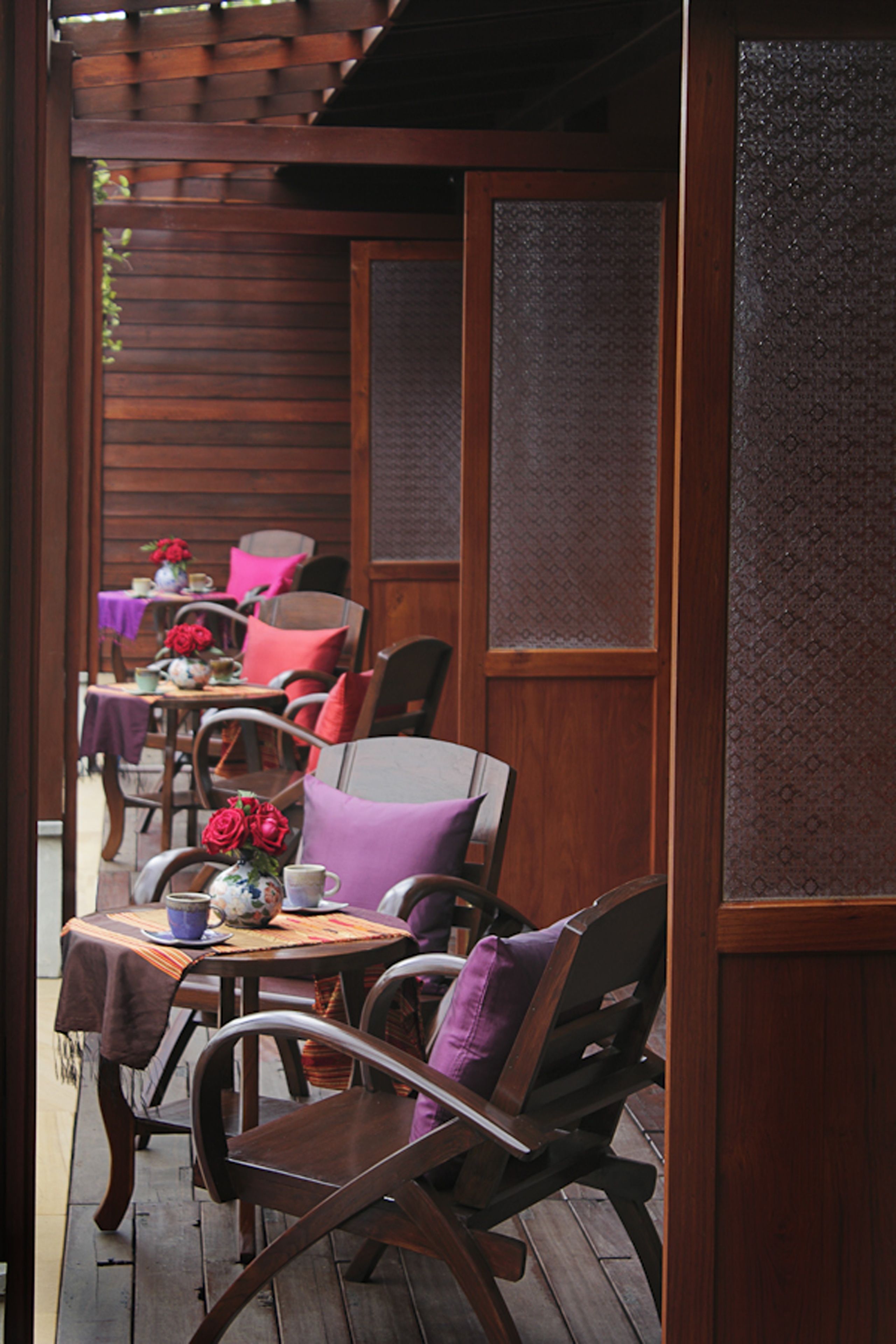 A wooden deck with outdoor seating, including tables and chairs, and a pergola overhead.
