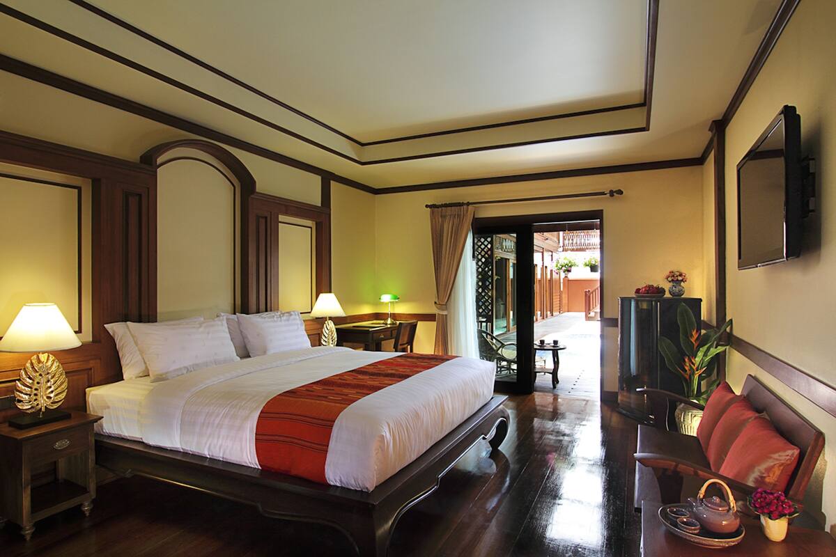 Una habitación de hotel con una cama grande, mesitas de noche, televisión, escritorio y una silla.