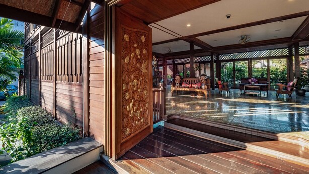 A spacious interior with a wooden floor, a decorative panel, and a seating area with a bench and chairs.