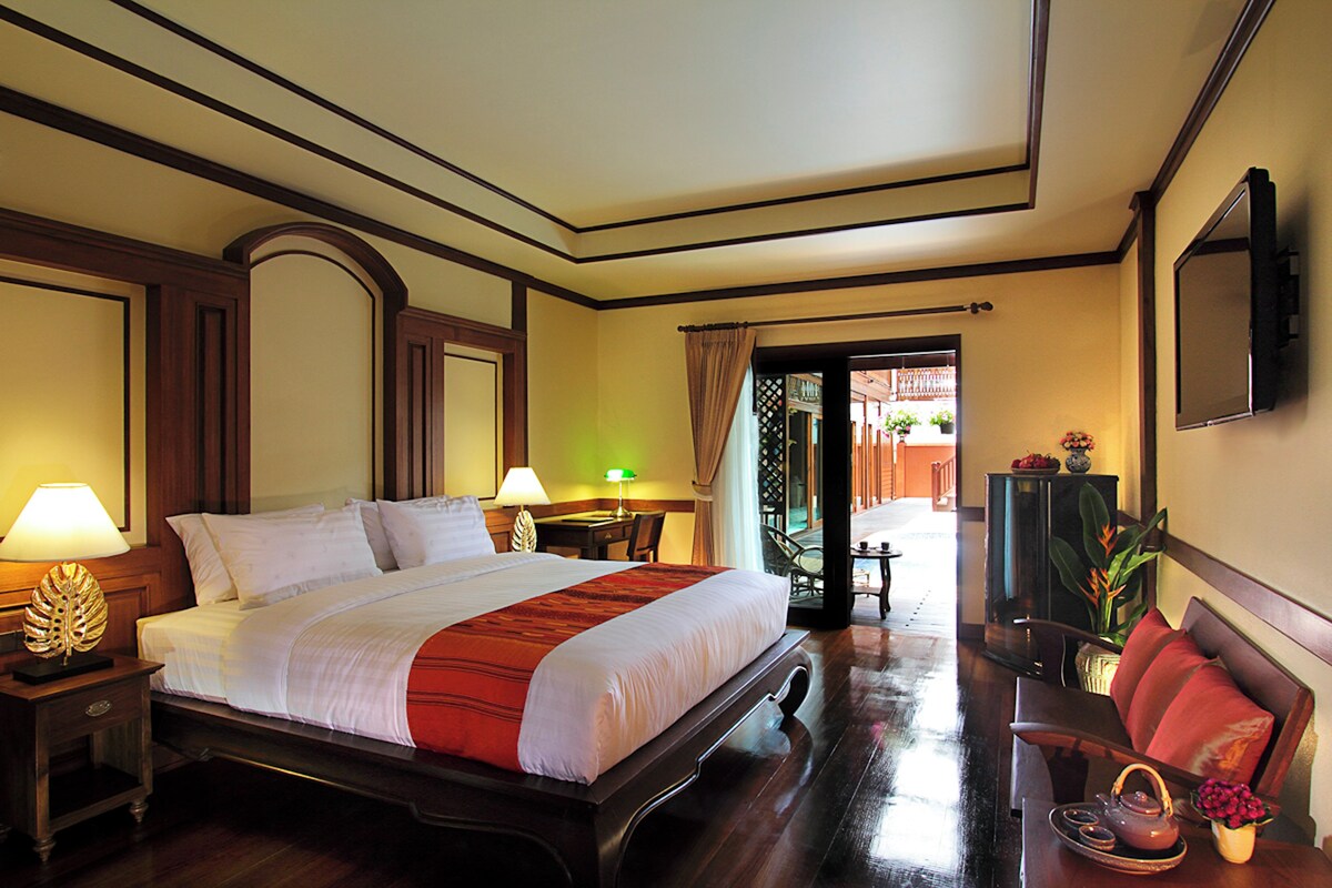 A hotel room with a large bed, bedside tables, a TV, a desk, and a chair.