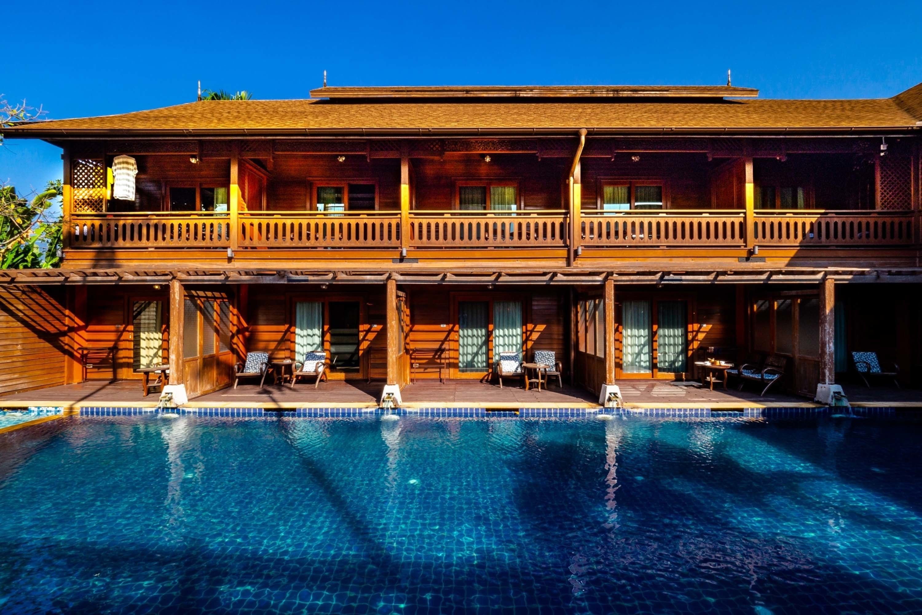 Ein zweistöckiges Holzhaus mit Schwimmbecken davor.
