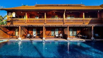 Un edificio in legno a due piani con una piscina di fronte.