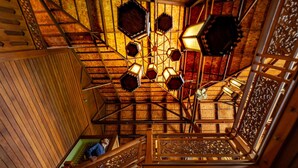 A multi-level wooden interior with a central staircase, wooden railings, and a decorative ceiling light fixture.