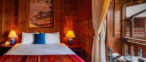 Habitación de hotel con una cama grande, dos lámparas de noche, un cabecero de madera, un cuadro de una escena tradicional y un balcón con vistas.