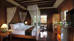 A wooden bedroom with a bed, nightstands, a desk, and a television.