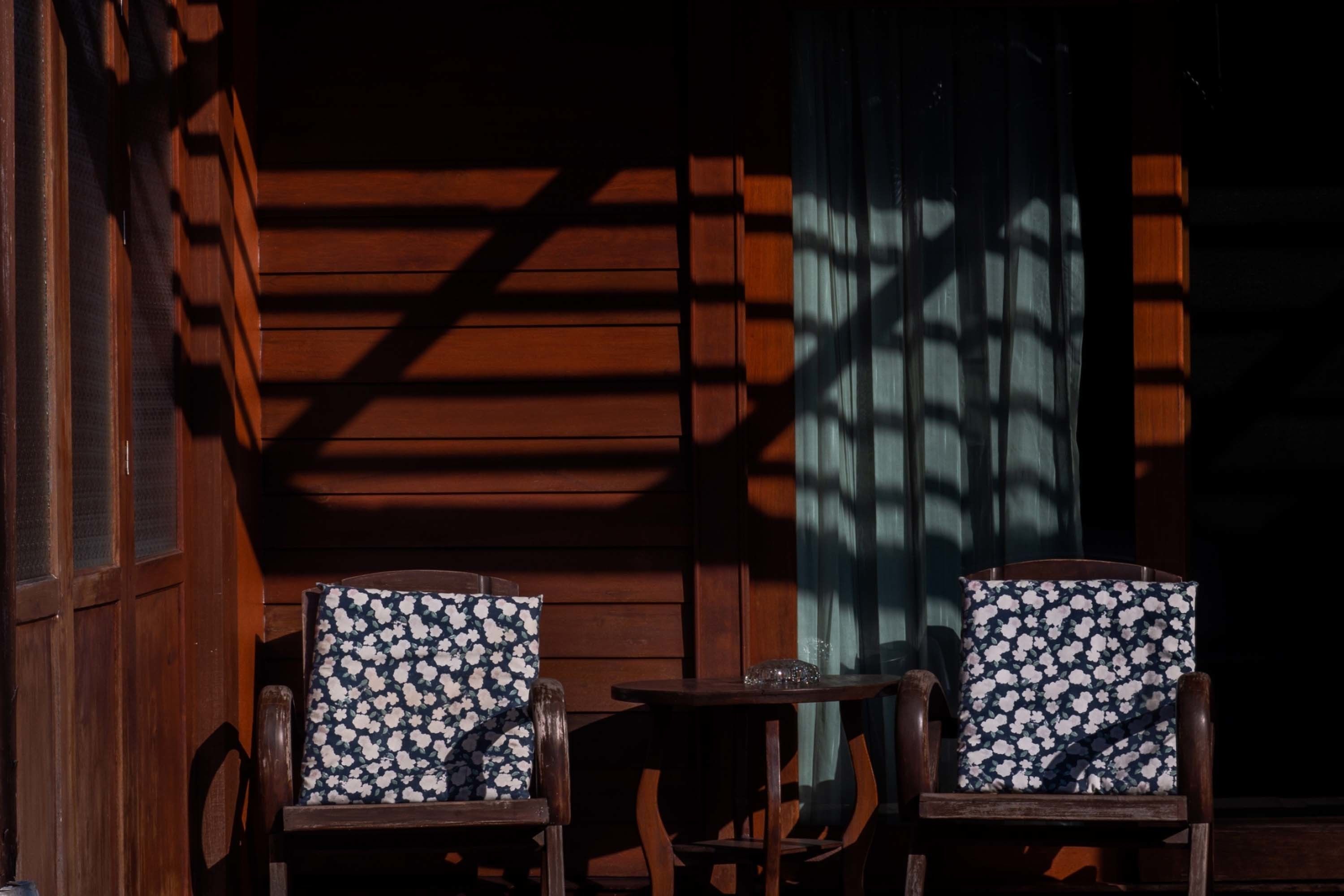 Two wooden chairs with floral upholstery, a small table, and a window with a grid pattern.