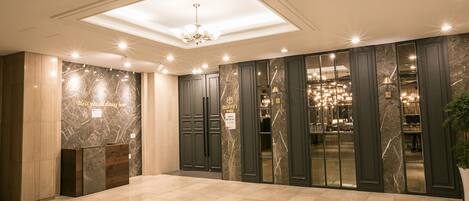 A lobby with marble walls, a reception desk, and a buffet area.