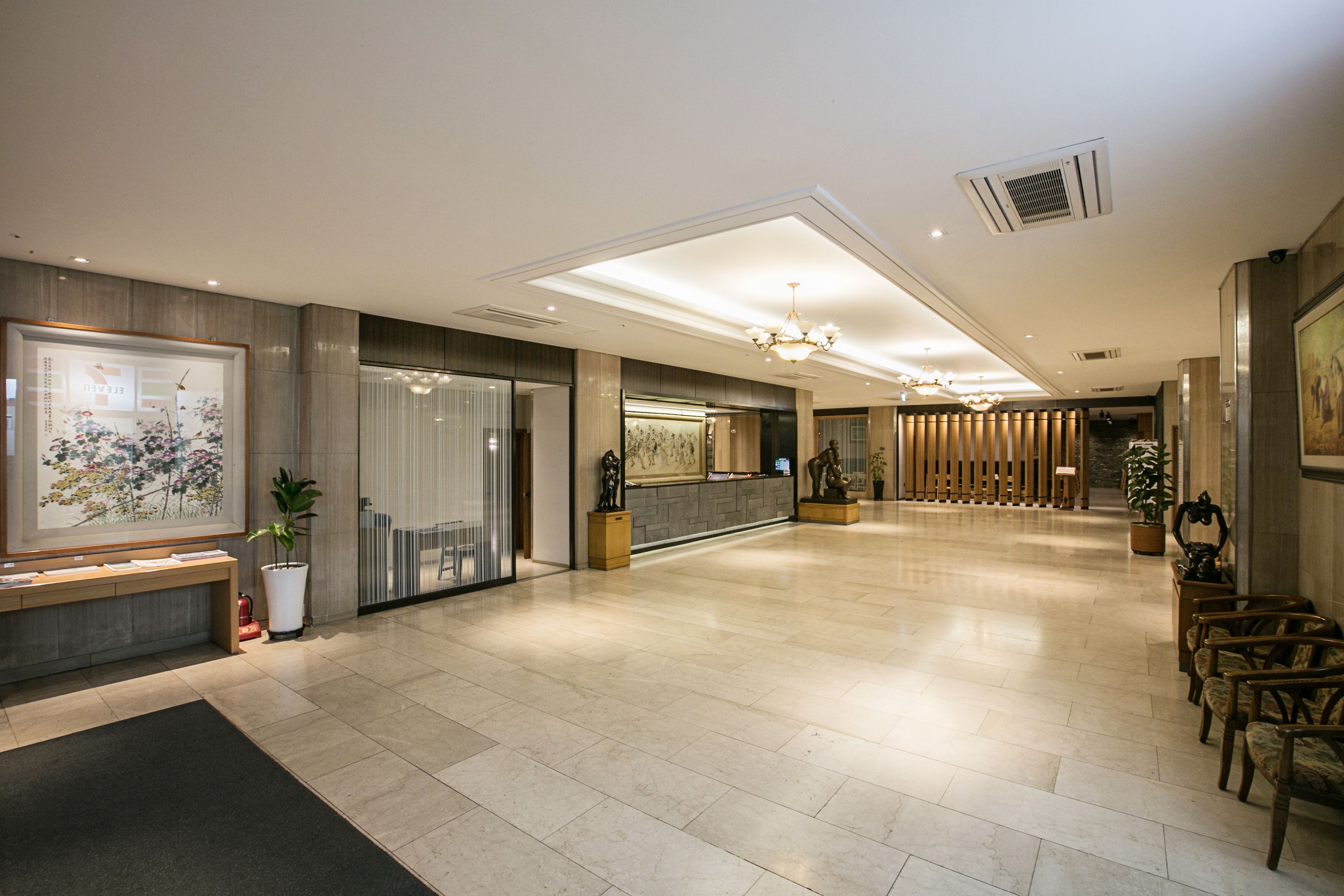 A spacious lobby with a reception desk, seating area, and a large framed artwork on the wall.