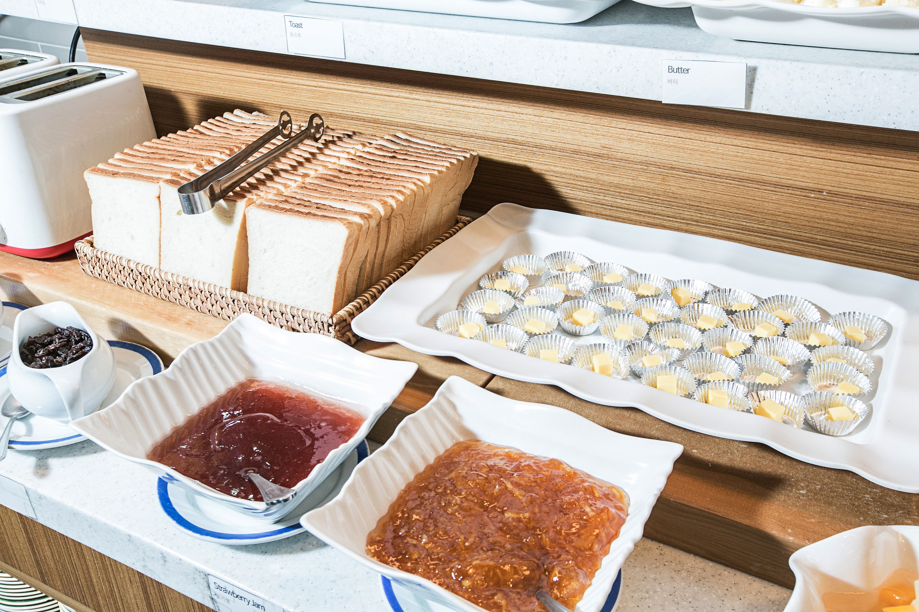 A kitchen counter with a loaf of bread, a tray of cupcakes, and bowls of jam.