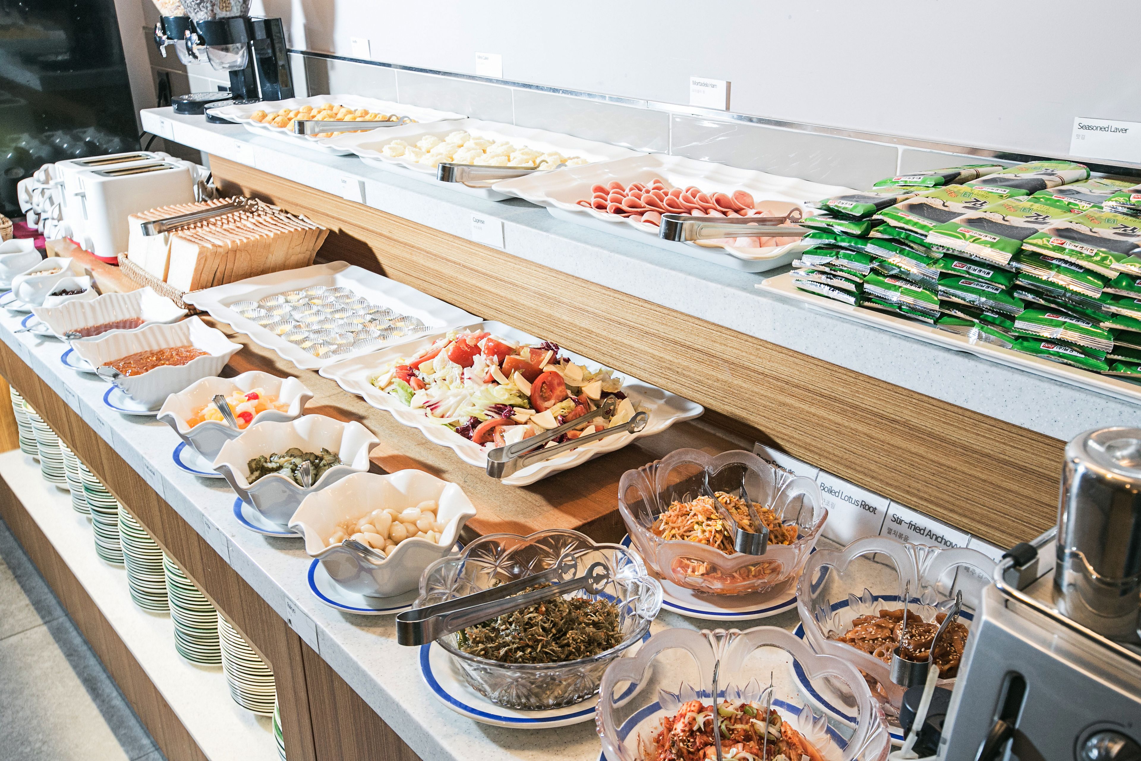 Buffet com diversas opções de comida, incluindo saladas, carnes e alimentos embalados.