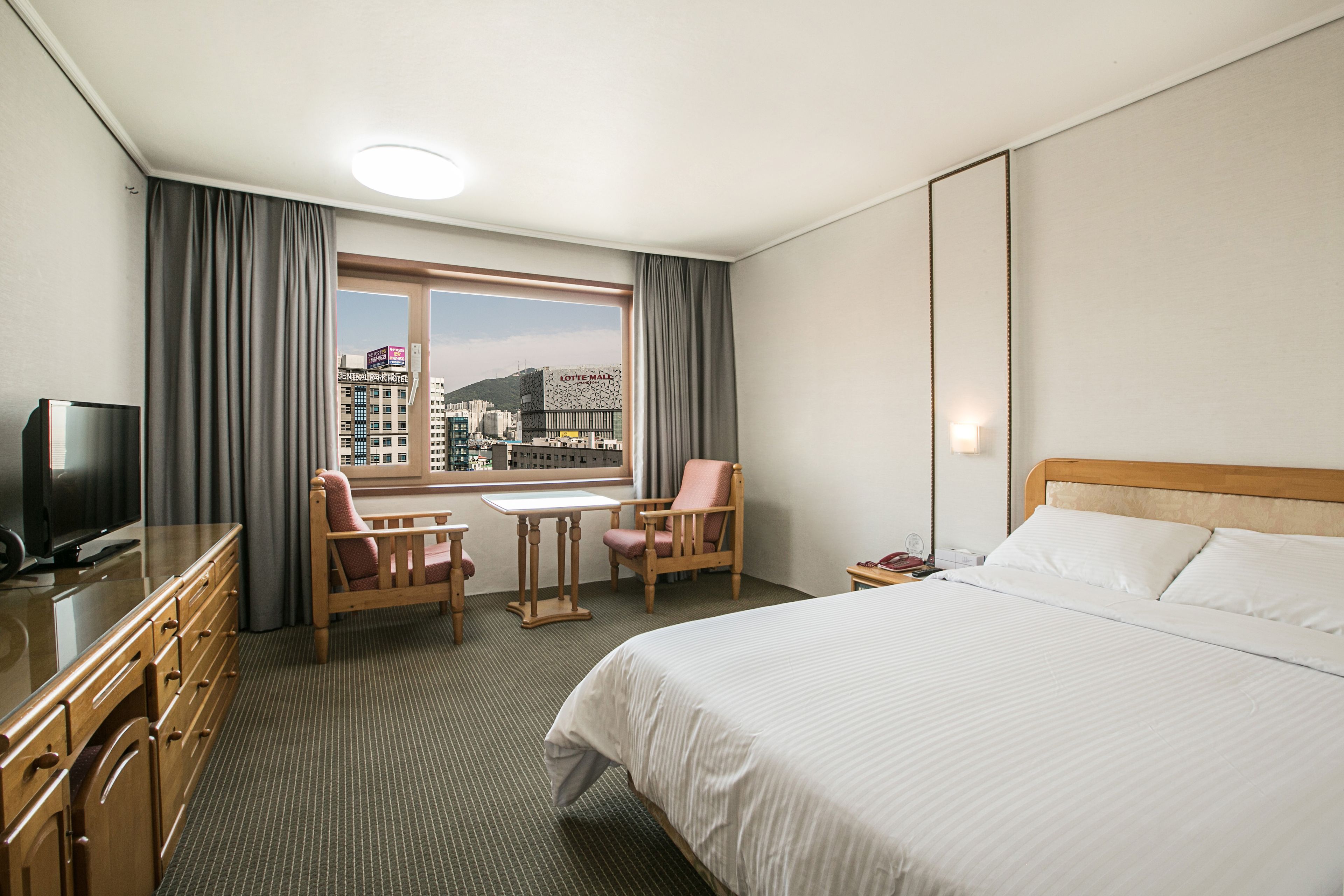 Una habitación de hotel con una cama, un escritorio, una silla y un televisor.