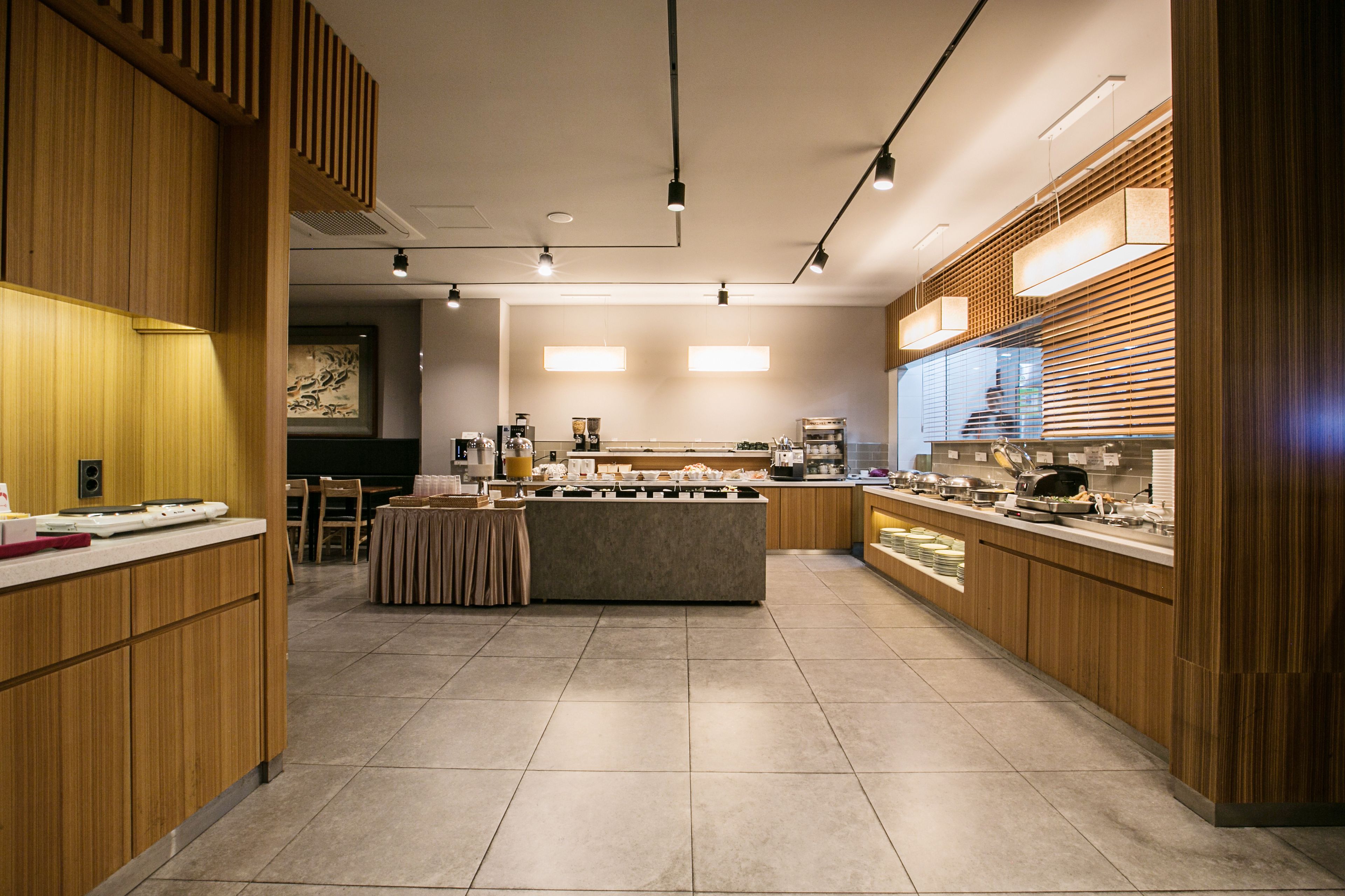 A modern kitchen with wooden cabinets, a central island, and a long counter with various appliances and utensils.