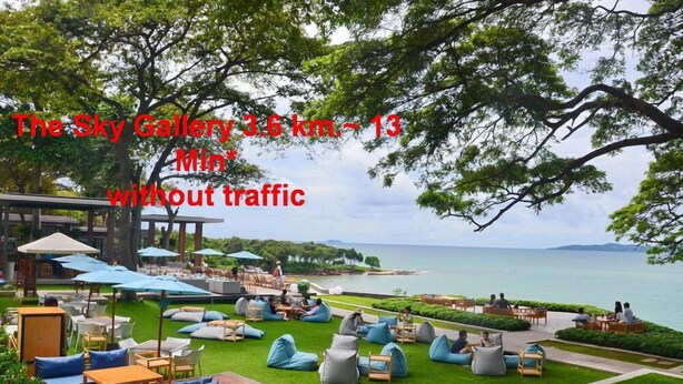A serene outdoor seating area with tables and chairs, surrounded by lush greenery and overlooking a body of water. - T5 Suites at Pattaya (Pattaya)