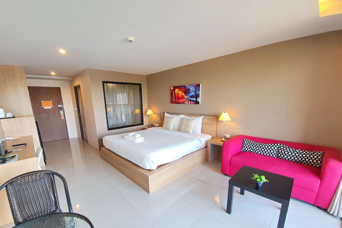 A hotel room with a bed, a sofa, a desk, and a chair.