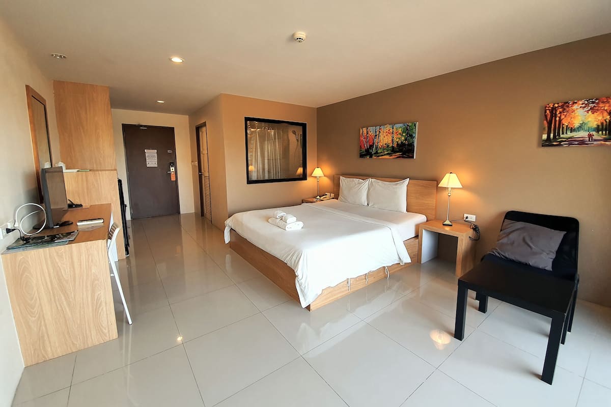 A hotel room with a large bed, bedside tables, a desk, and a chair.