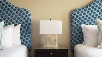 A hotel room with two beds, a nightstand, and a lamp.