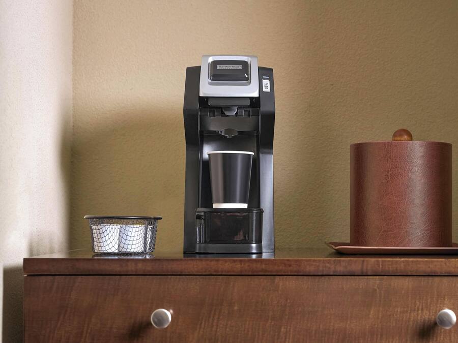 Een koffiezetapparaat, een kaars en een gaasbakje op een houten oppervlak.