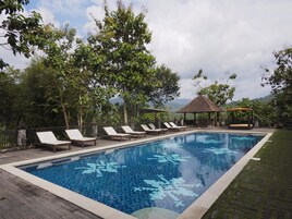 Una piscina al aire libre, sillones reclinables de piscina