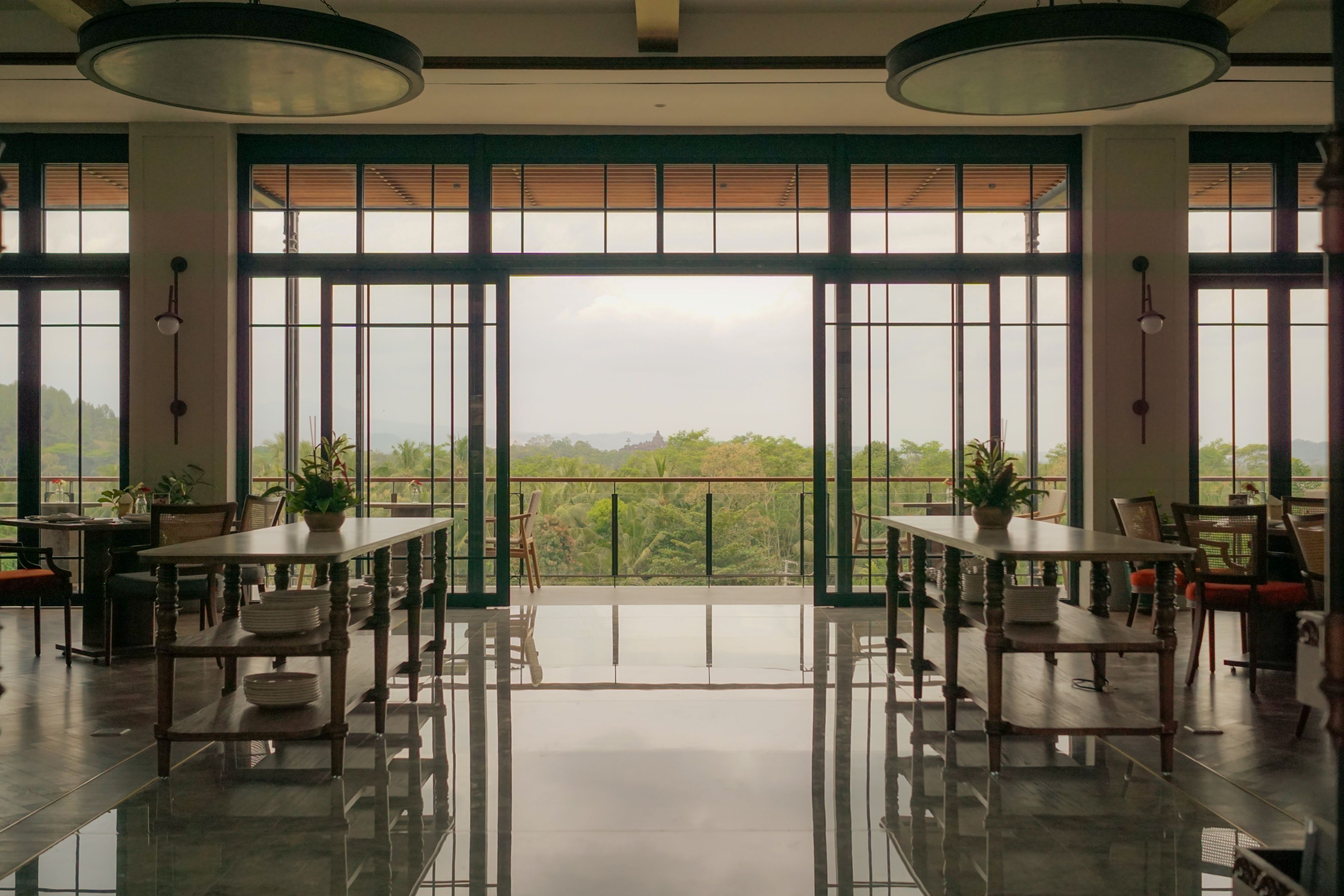 A spacious dining area with a view of greenery and mountains through large windows.