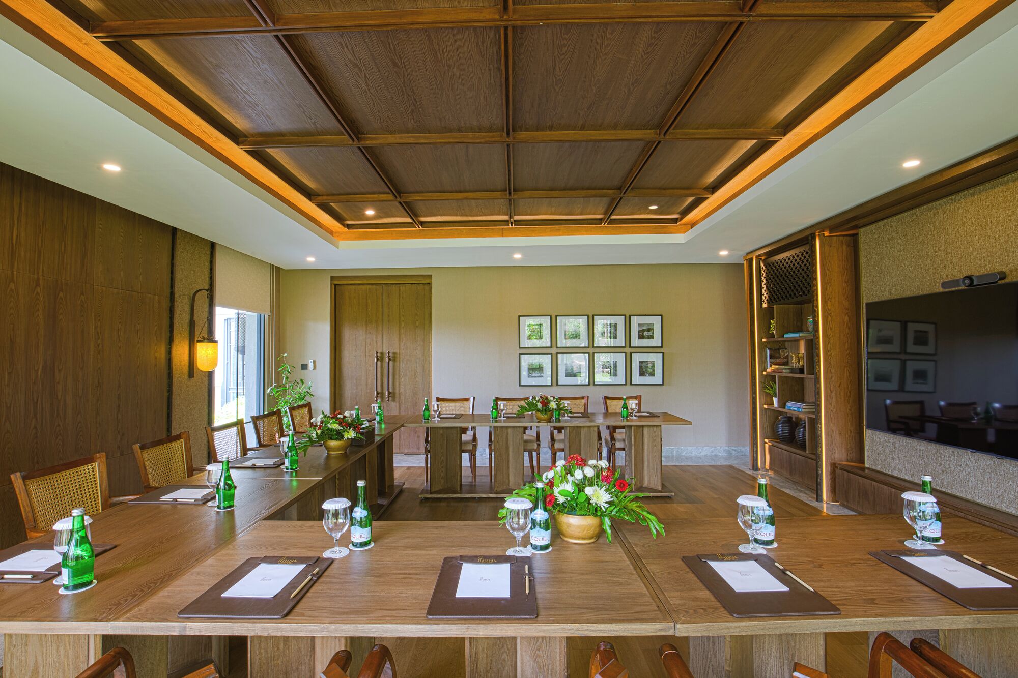 A conference room with a long table, chairs, and a wooden ceiling.