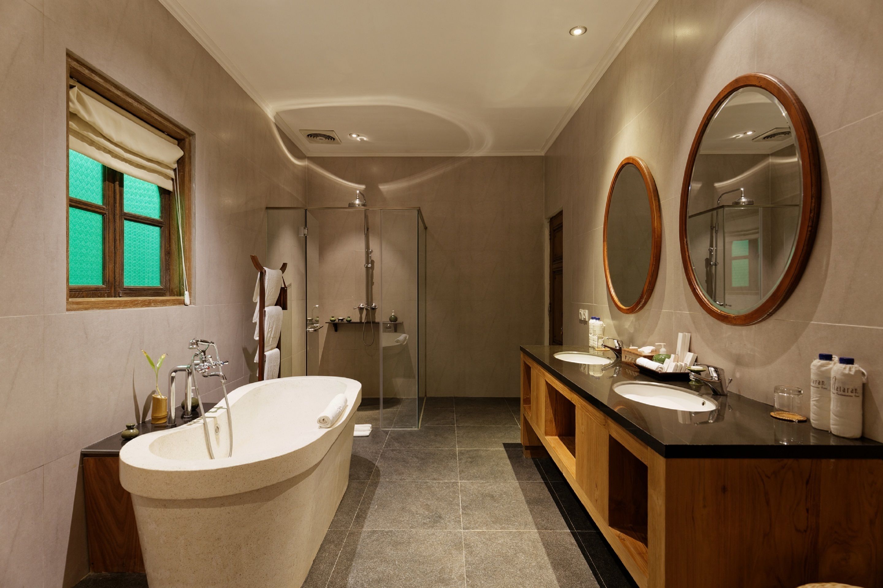 A modern bathroom with a freestanding bathtub, a glass-enclosed shower, and a vanity with two sinks.