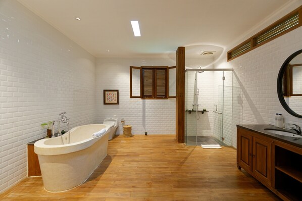 Un baño moderno con una bañera independiente, un box de ducha de vidrio y muebles de madera.